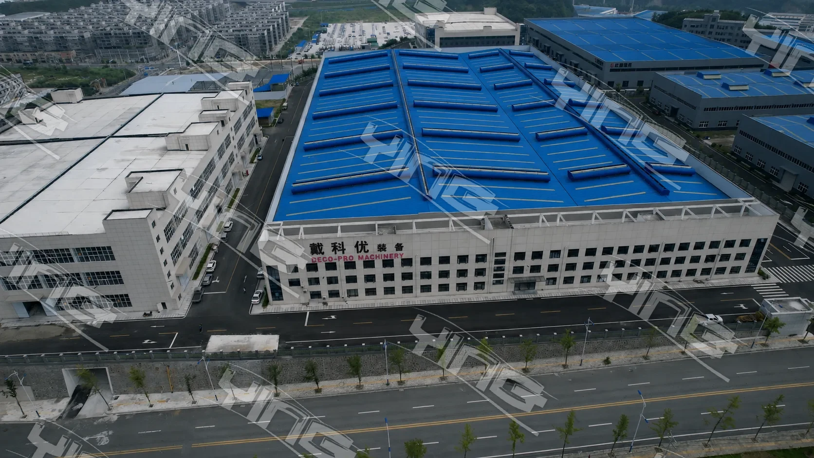 Aerial view of the DECO-PRO machinery plant in Shiyan, Hubei — a long building with a blue roof and the DECO-PRO MACHINERY sign on its front