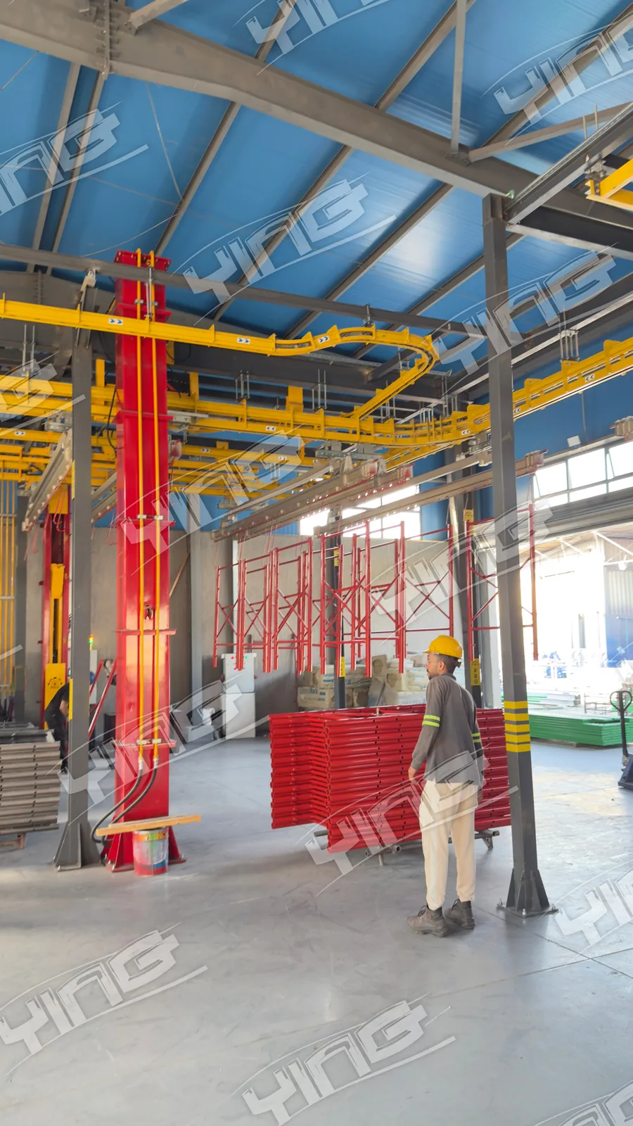 Red elevator lifter columns under the yellow overhead conveyor in the ACROW Misr loading hall